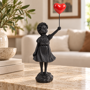 Held in Hope girl with heart balloon sculpture in black & red, displayed in a styled interior