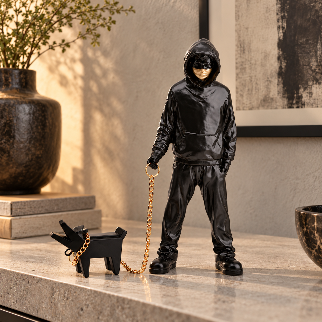 Urban Companion hooded figure and dog sculpture in black & gold, displayed in a styled interior