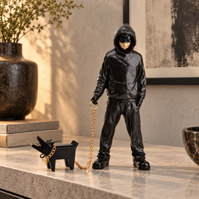 Urban Companion hooded figure and dog sculpture in black & gold, displayed in a styled interior